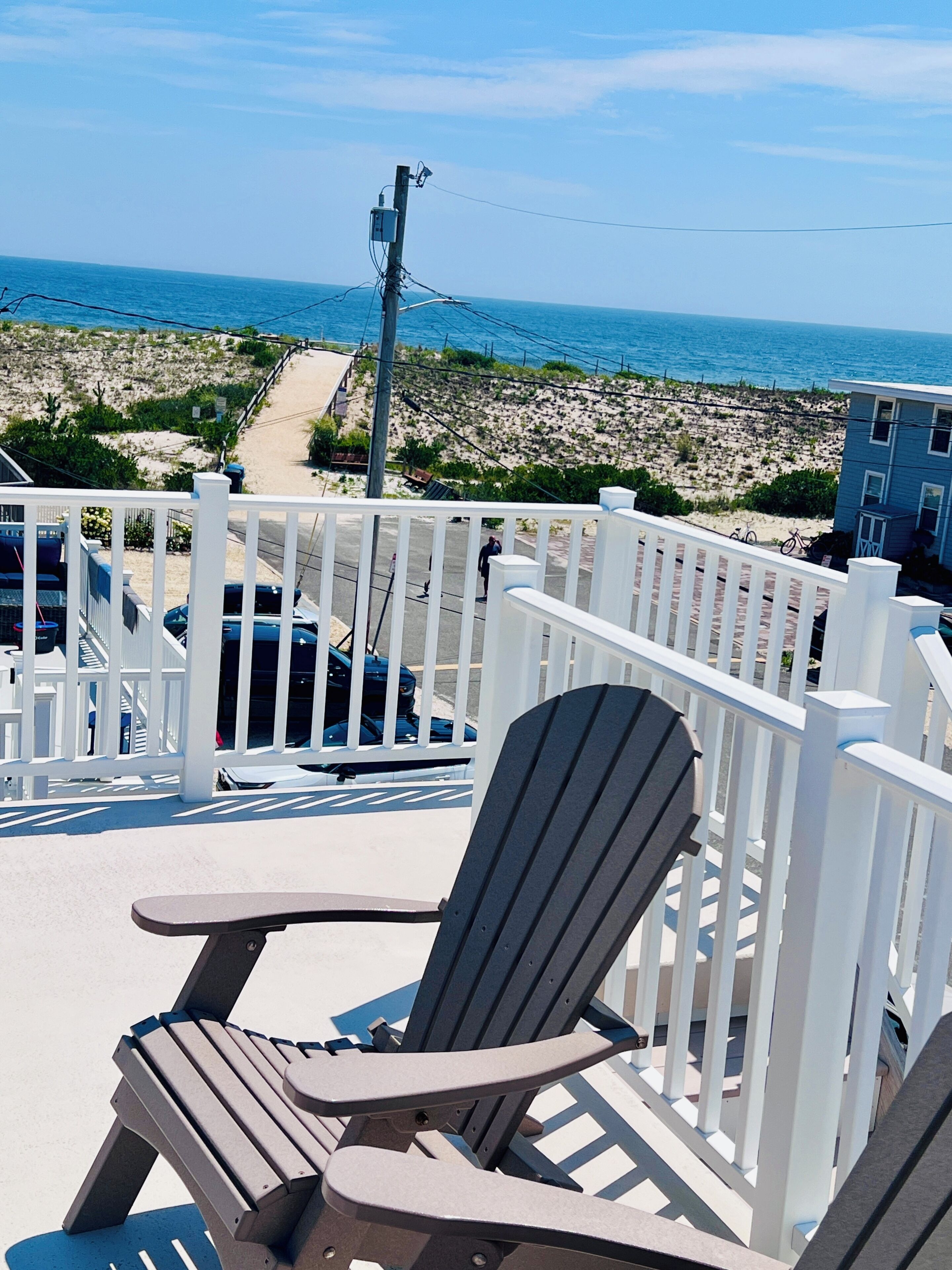 Une terrasse avec vue sur la plage et l’océan, une chaise et une rambarde.