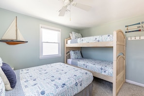 Quarto com duas beliches, decoração náutica de um veleiro, janela e ventilador de teto.