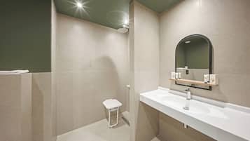 Un baño moderno con ducha, lavamanos y espejo.