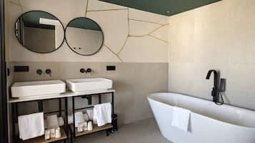 Un baño moderno con dos lavamanos, una bañera independiente y dos espejos montados en la pared.