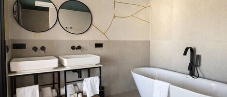 A modern bathroom with two sinks, a freestanding bathtub, and two wall-mounted mirrors.