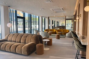 Un interior moderno con un sofá grande, otomanas redondas y una zona de bar.