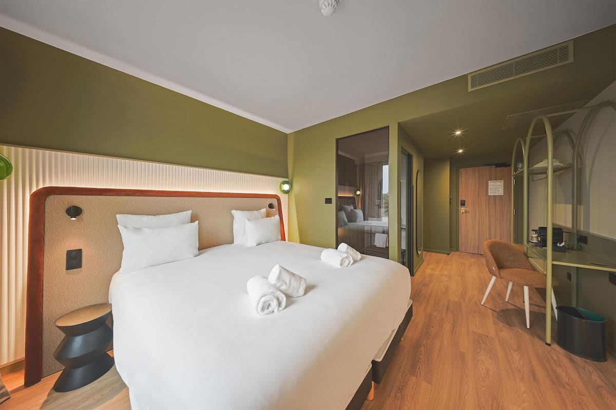 Une chambre d’hôtel avec un grand lit, un bureau et une chaise.
