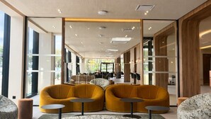Un vestíbulo amplio con asientos modernos, un techo alto con diseño perforado y ventanas grandes que permiten la entrada de luz natural.