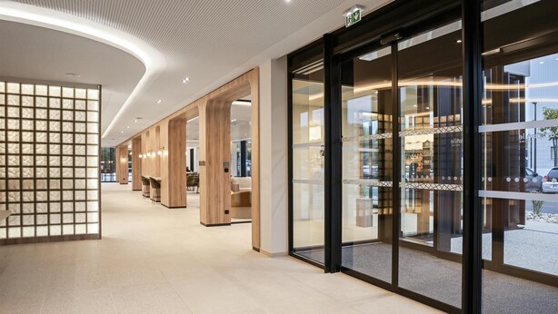 Un interior moderno con techo curvo, paneles de madera y puertas de cristal que dan a un espacio exterior.