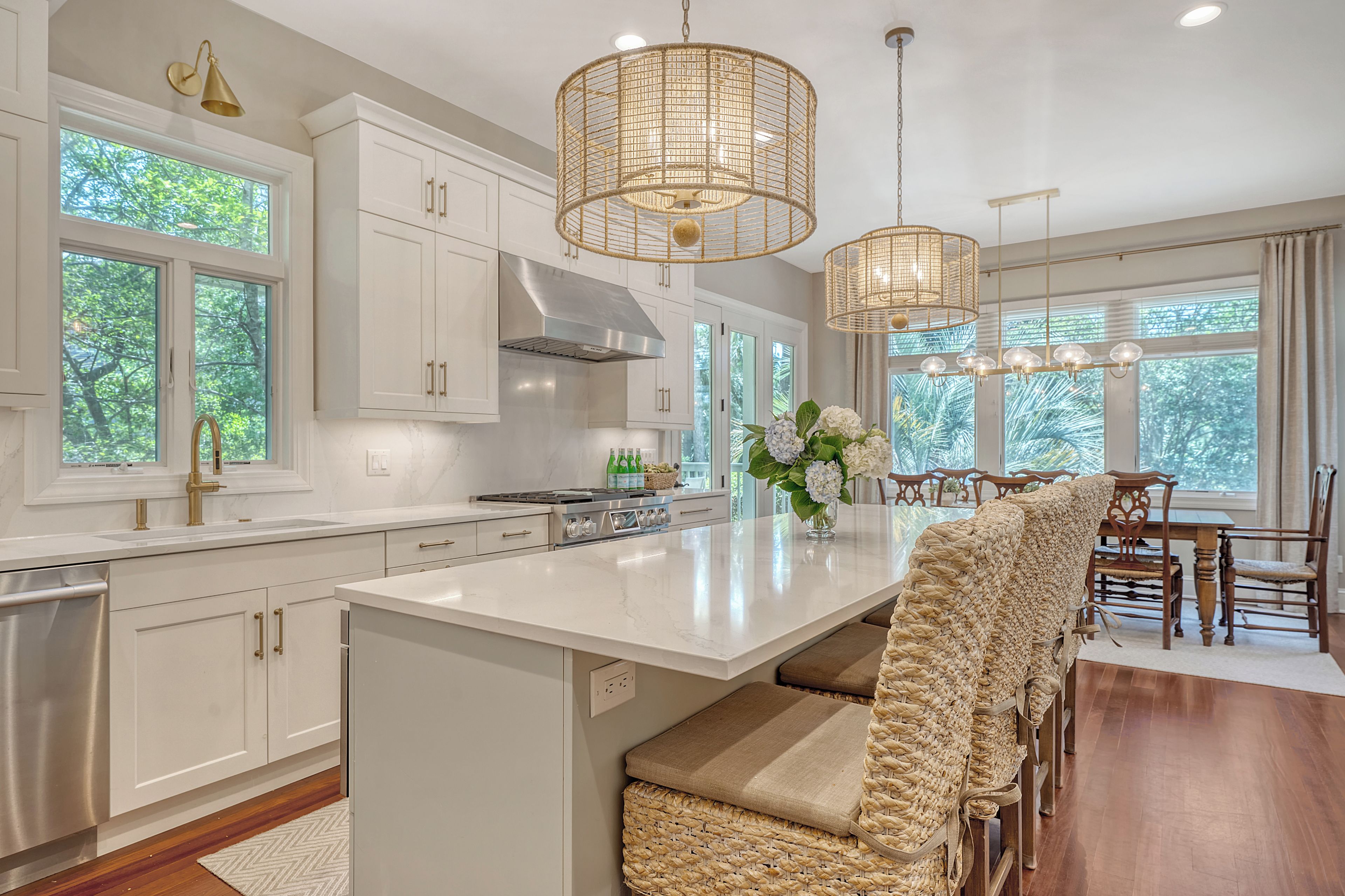 A modern kitchen with white cabinetry, a large island, and a dining area with wooden chairs.