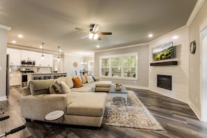 A modern living room with a sectional sofa, a coffee table, and a fireplace.