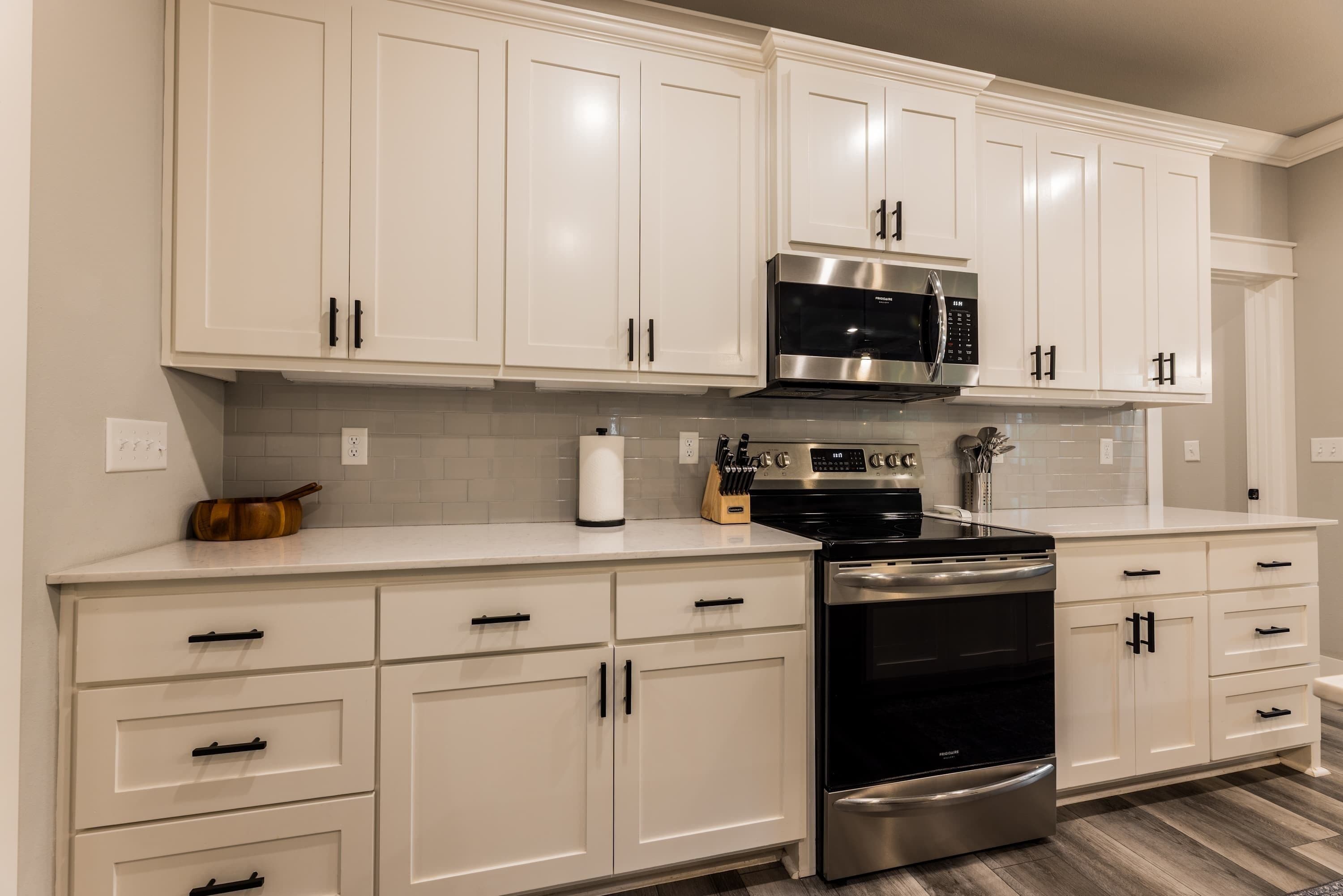 A kitchen with white cabinets, a stainless steel stove, and a microwave.