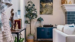 En stue med en hvid sofa, et blåt skab, en potteplante og et billede på væggen.