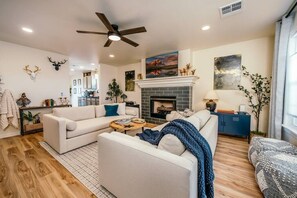 Una sala de estar moderna con chimenea, dos sofás, una mesa de centro y un ventilador de techo.