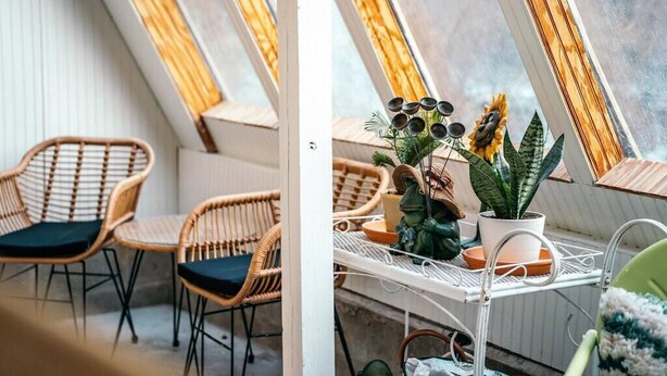 Une pièce chaleureuse avec un plafond en pente et une petite table ornée de plantes en pot.