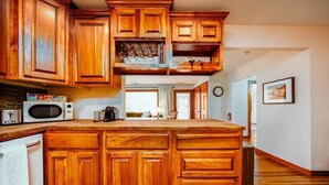 Une cuisine avec des meubles de rangement en bois, un four à micro-ondes et une machine à café.