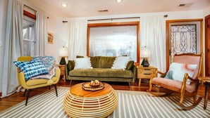 Un salon avec un canapé, des fauteuils, une table basse et une fenêtre avec des rideaux.