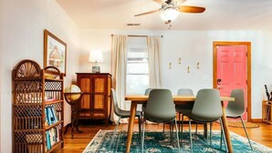 Un coin repas avec une table en bois, quatre chaises, un globe terrestre posé sur un socle, une bibliothèque et un ventilateur de plafond.
