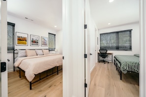 Una habitación con cama, escritorio y ventana con persianas.