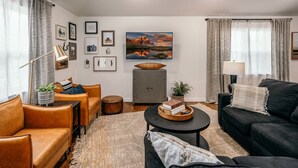 Un salon moderne avec des canapés en cuir, une table basse et un grand tableau accroché au mur.