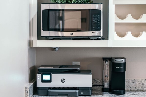 Una cocina equipada con microondas, impresora HP y cafetera KEURIG.