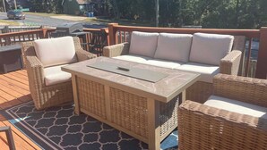 A deck with wicker furniture, including a sofa and chairs, a table, and a grill.