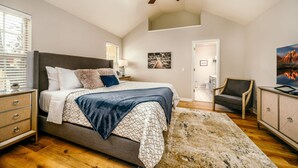 Une chambre à coucher comprenant un lit, un ventilateur de plafond, une table de chevet, une chaise, un meuble et un tableau accroché au mur.
