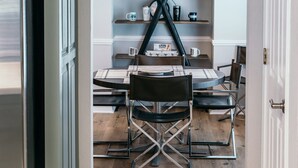 Un espace repas avec une table en bois, des chaises noires et un lustre moderne.