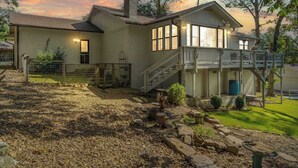 A two-story house with a covered porch and a fenced backyard. - The Coves on Beaver Lake (Rogers)