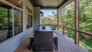 Une terrasse couverte avec une table et des chaises, de grandes fenêtres et un ventilateur de plafond.