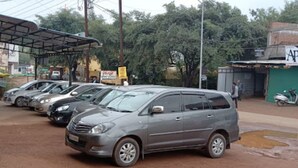 Une rangée de voitures garées sur un parking, avec un bâtiment en arrière-plan.