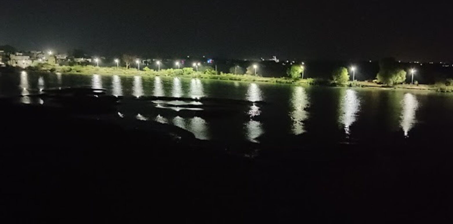 A nighttime view of a river with reflections of lights on the water.