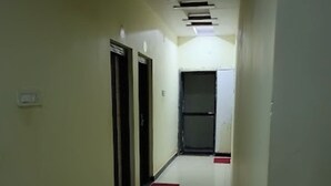 Un couloir avec un sol blanc, des tapis rouges et des portes sur le côté gauche.