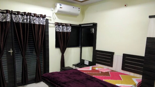 Une chambre à coucher avec un lit, une table de chevet, une commode et une fenêtre avec des rideaux.