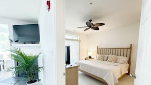 A bedroom with a bed, a ceiling fan, a TV, and a potted plant. - Condo with Community Pool - 17432 Slipper Shell Way Unit 1 (Lewes)