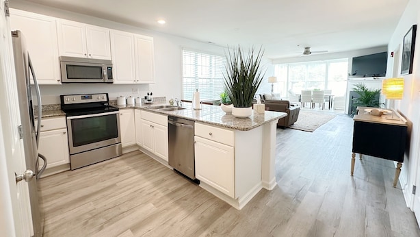 A modern kitchen with white cabinetry, stainless steel appliances, and a central island. - Condo with Community Pool - 17432 Slipper Shell Way Unit 1 (Lewes)