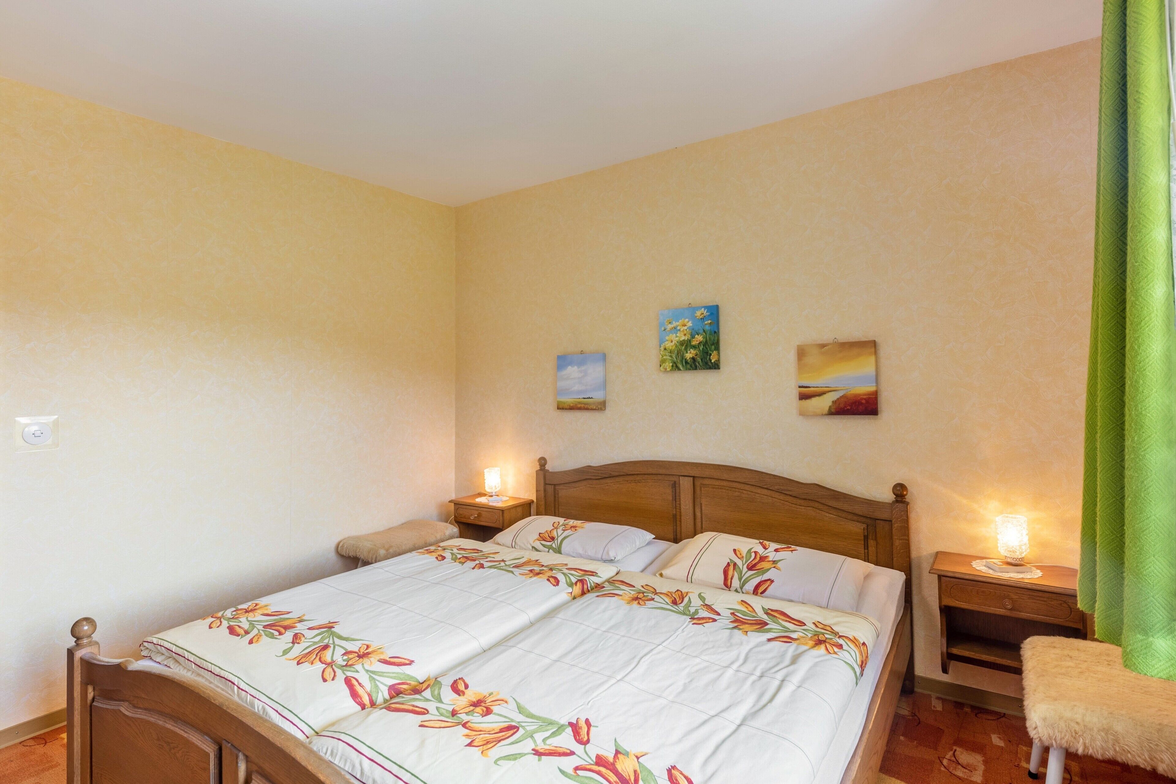 Un dormitorio con una cama de madera, dos mesitas de noche y una cortina verde.