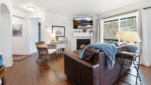Una sala de estar con chimenea, un sofá, una mesa de centro y una televisión.