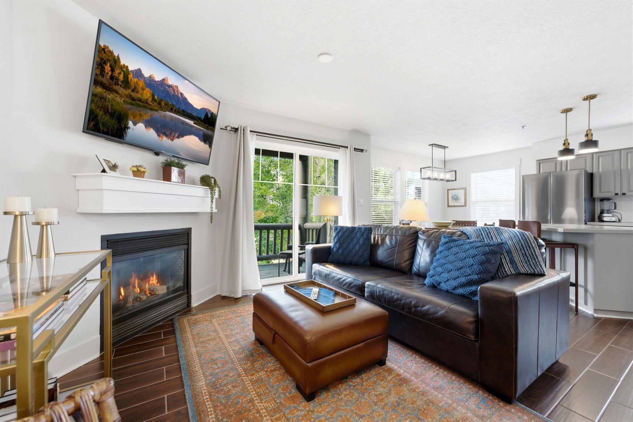 A modern living room with a fireplace, leather sofa, and a large TV mounted on the wall.