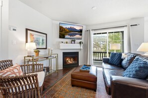 A living room with a fireplace, a sofa, a coffee table, and a dining area with chairs. - Jordanelle Escape: Lake Life, Mountain Highs (Heber City)