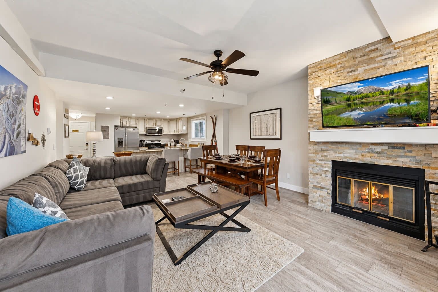 A modern living room with a fireplace, a dining area, and a kitchen in the background.