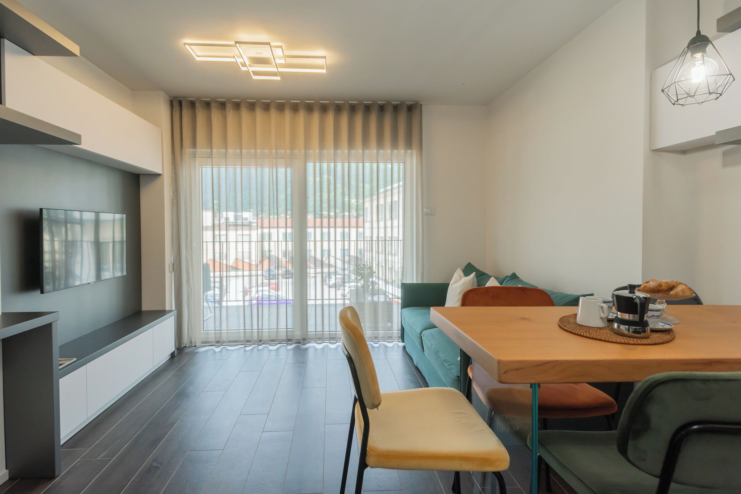 Una sala de estar moderna con televisor, sofá y comedor con mesa y sillas.