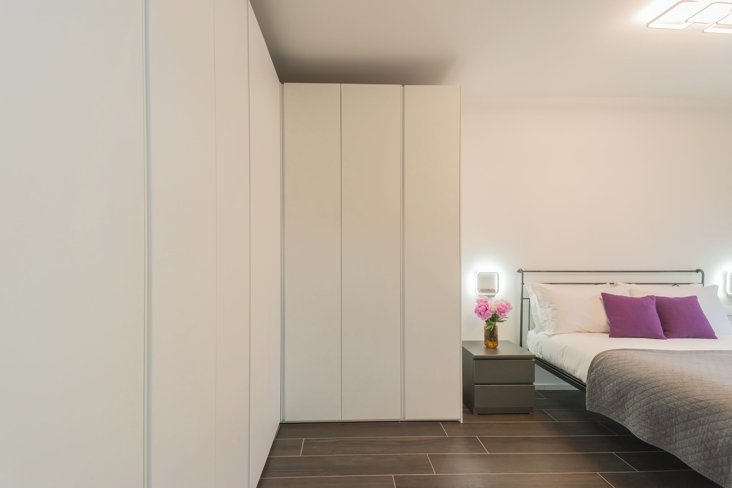 Een moderne slaapkamer met een bed, nachtkastjes en een wandmeubel.