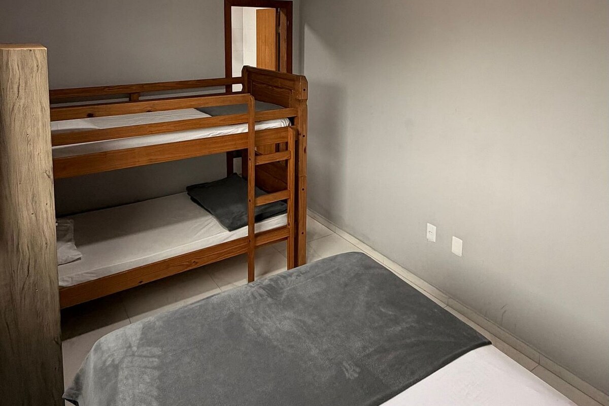 Un dormitorio con literas, un cabecero de madera, un espejo y una lámpara en el techo.