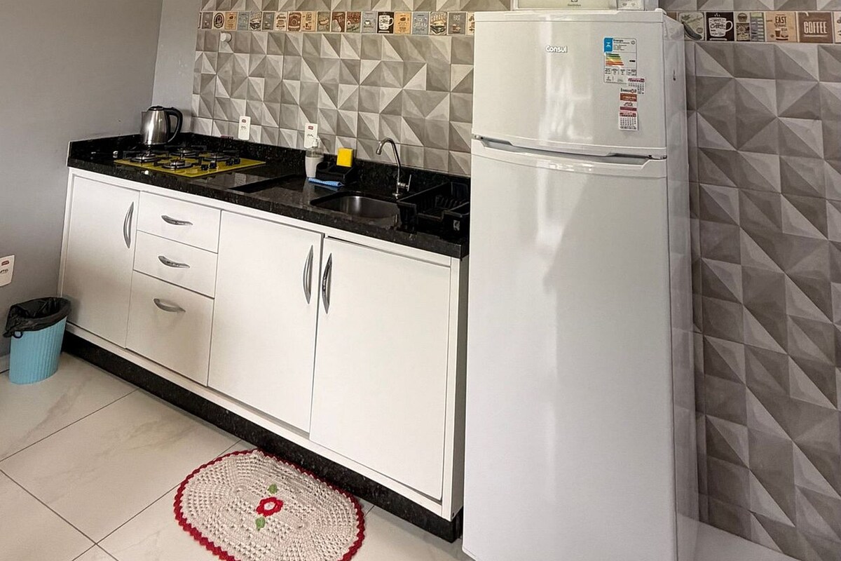 Una cucina moderna con mobili bianchi, un piano di lavoro nero, un forno a microonde e una macchina per il caffè.