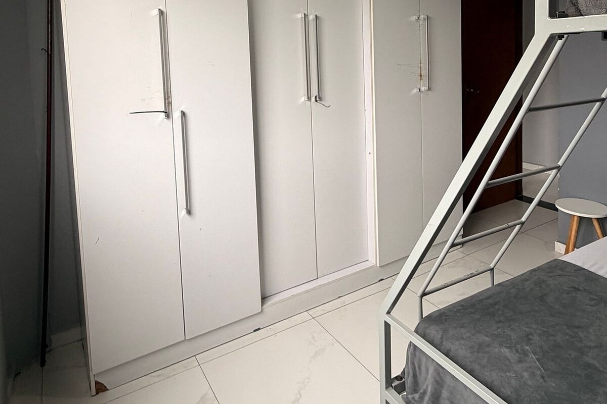 Un dormitorio con una cama litera, un armario de múltiples puertas y una lámpara en el techo.