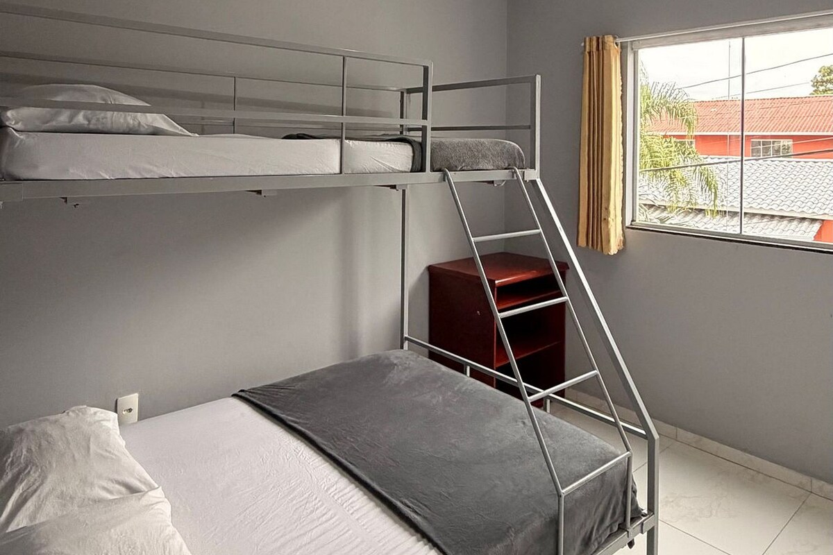 Habitación con literas, una ventana y un caja roja para guardar objetos.