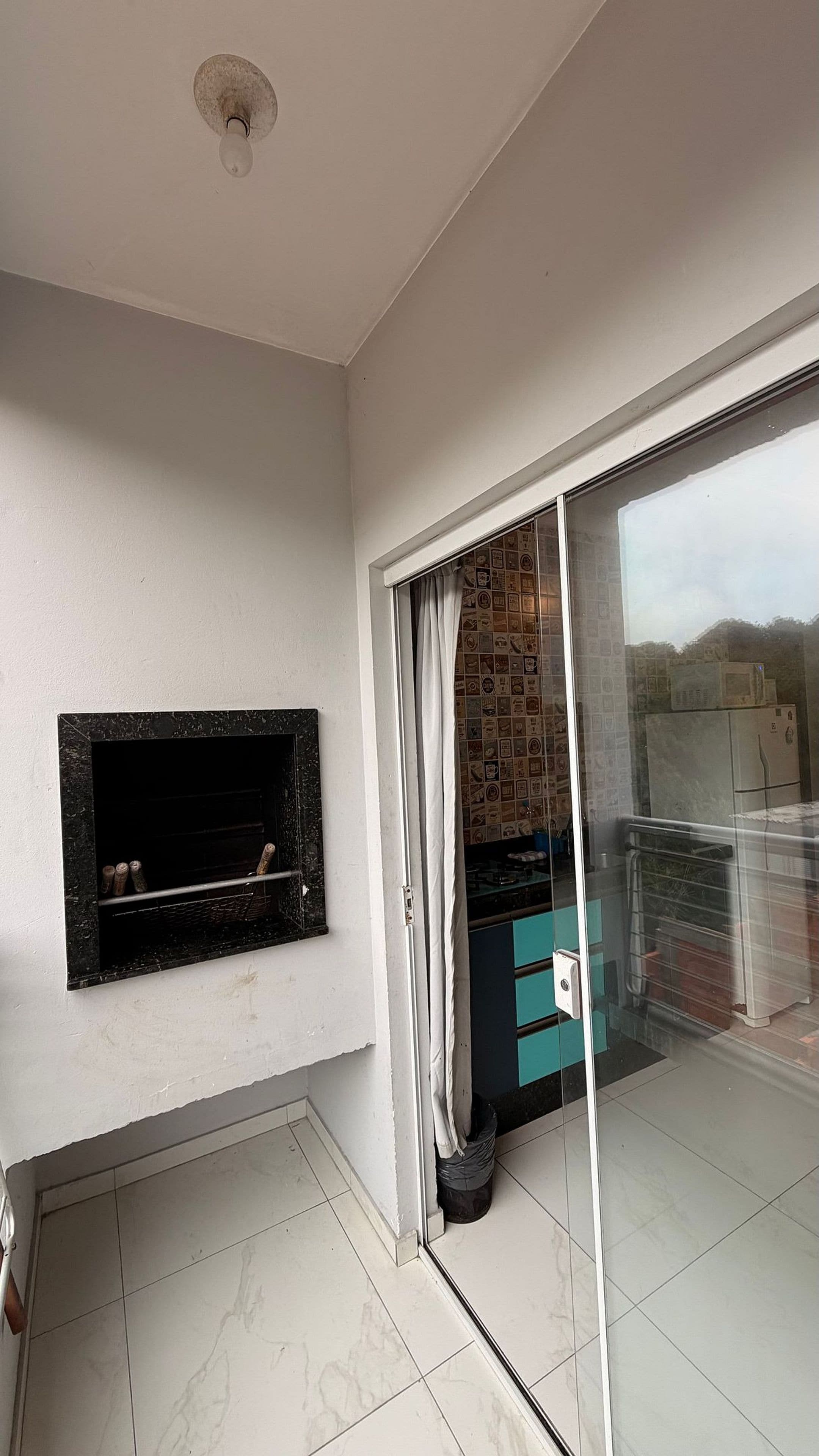 A room with a fireplace, a sliding glass door leading to a balcony, and a tiled floor.
