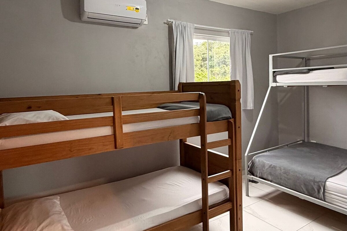 Una habitación con dos literas, una ventana con cortinas, un aire acondicionado y una lámpara en el techo.