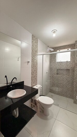 A modern bathroom with a black countertop, white sink, and toilet. - Residencial Águia - Piske Imóveis (Florianopolis)
