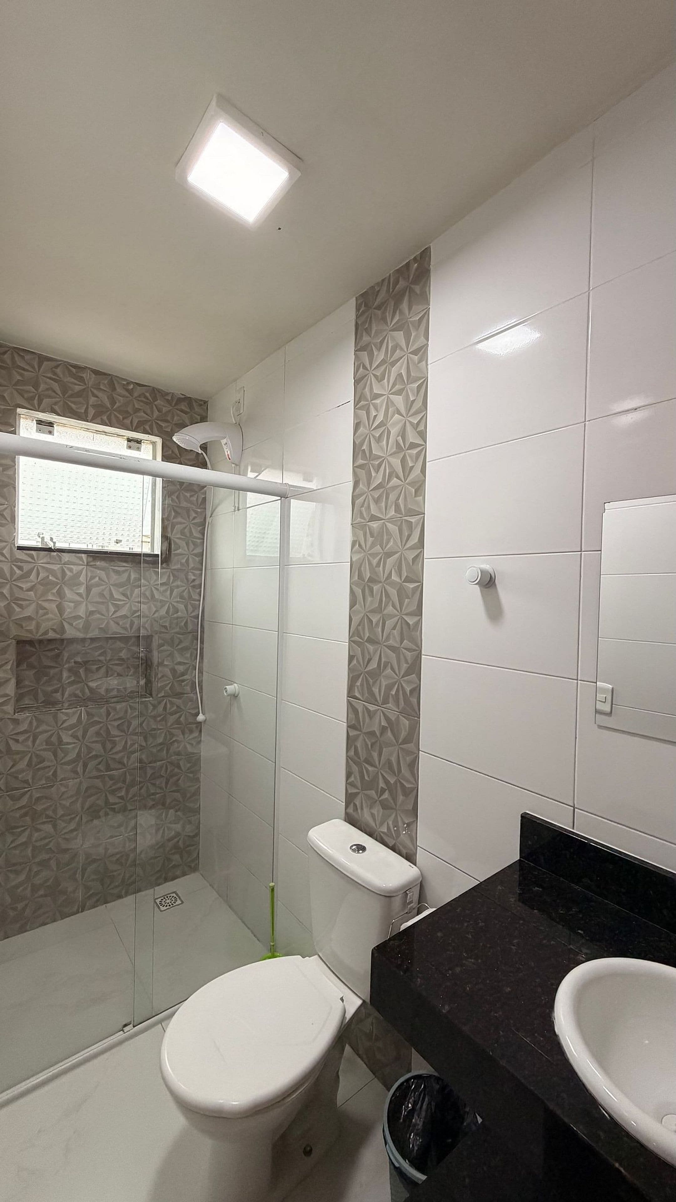 Een badkamer met toilet, douchecabine, wastafel en spiegel.