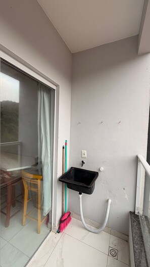 Ein kleines Badezimmer mit Waschbecken, Besen und Stuhl.