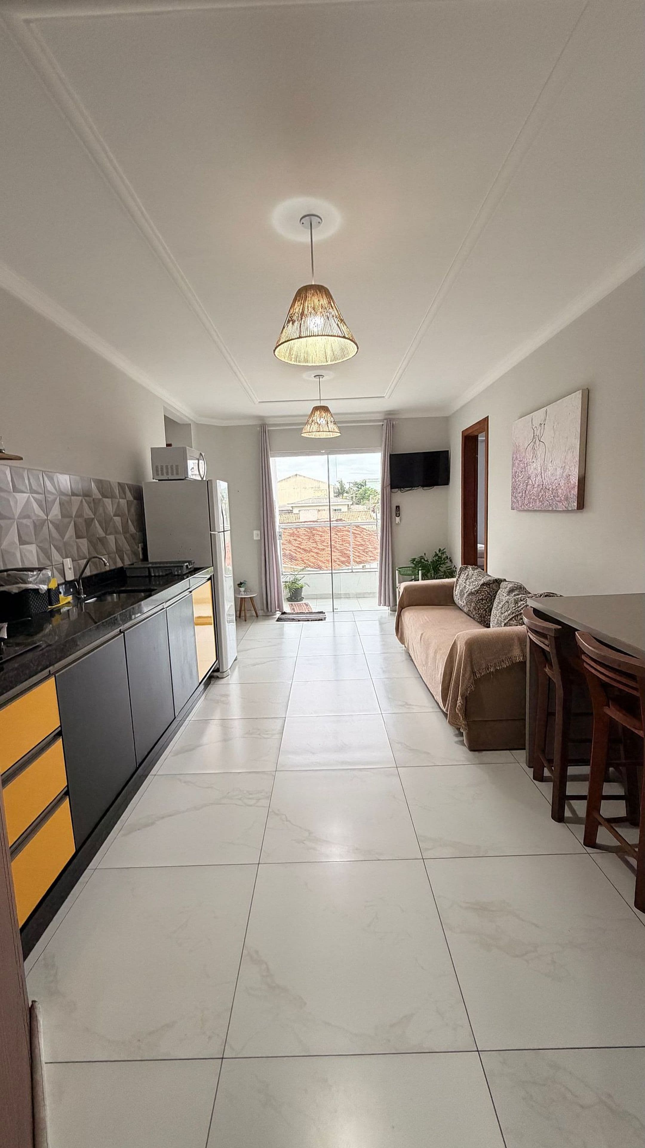 Cozinha moderna com área de jantar, um sofá e vista para o exterior.