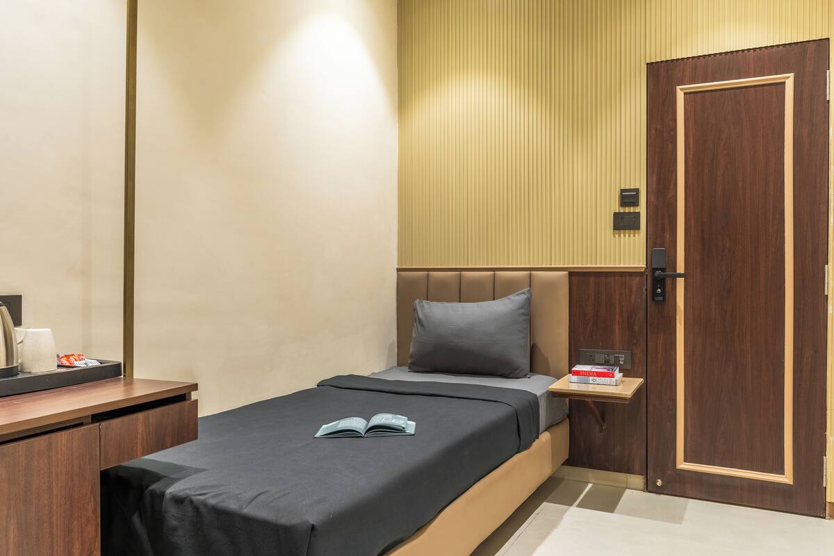 A modern hotel room with a bed, bedside table, and a door.